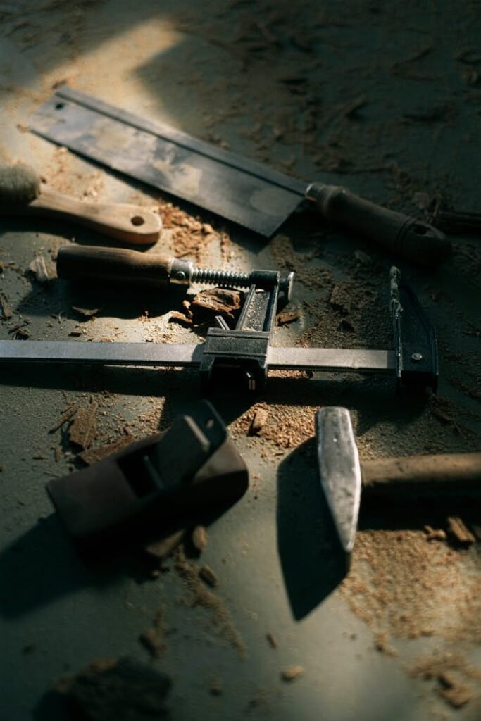 A collection of vintage woodworking tools scattered on a workbench under dim light.